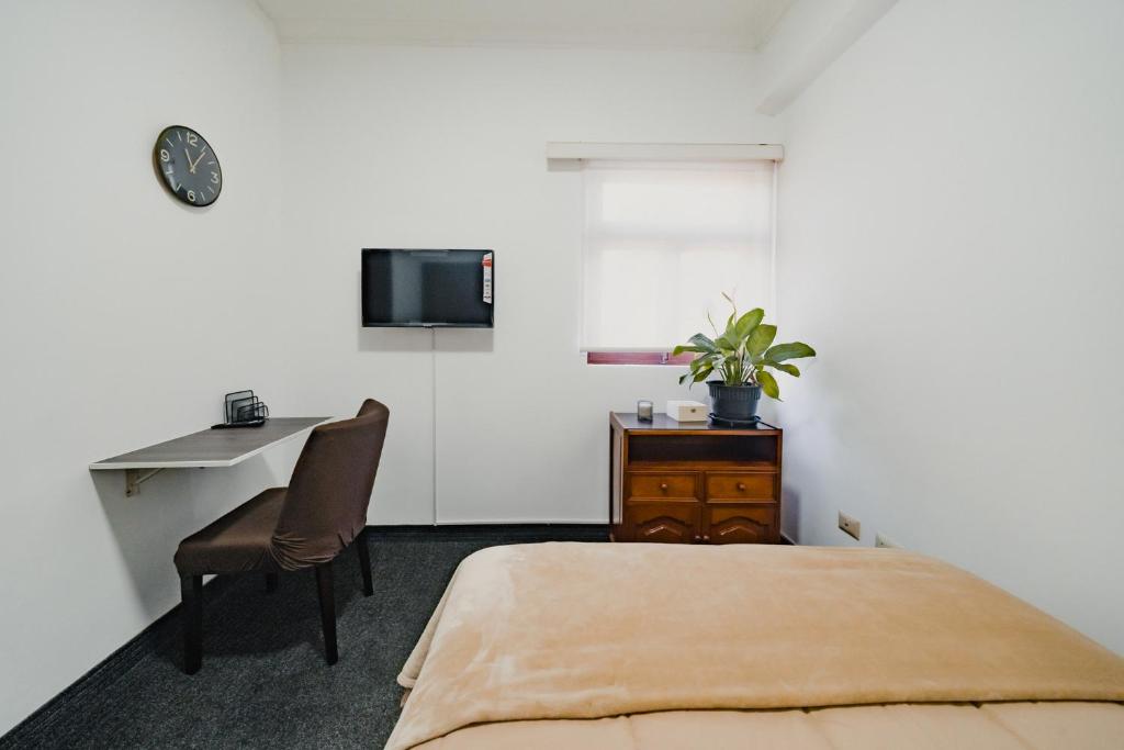 利马Miraflores Kennedy Park的一间卧室配有一张床、一张书桌和一台电视。