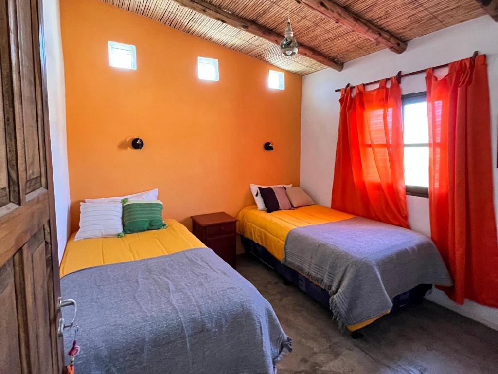 卡奇Cabaña Paraíso Cachi的橙色墙壁客房的两张床