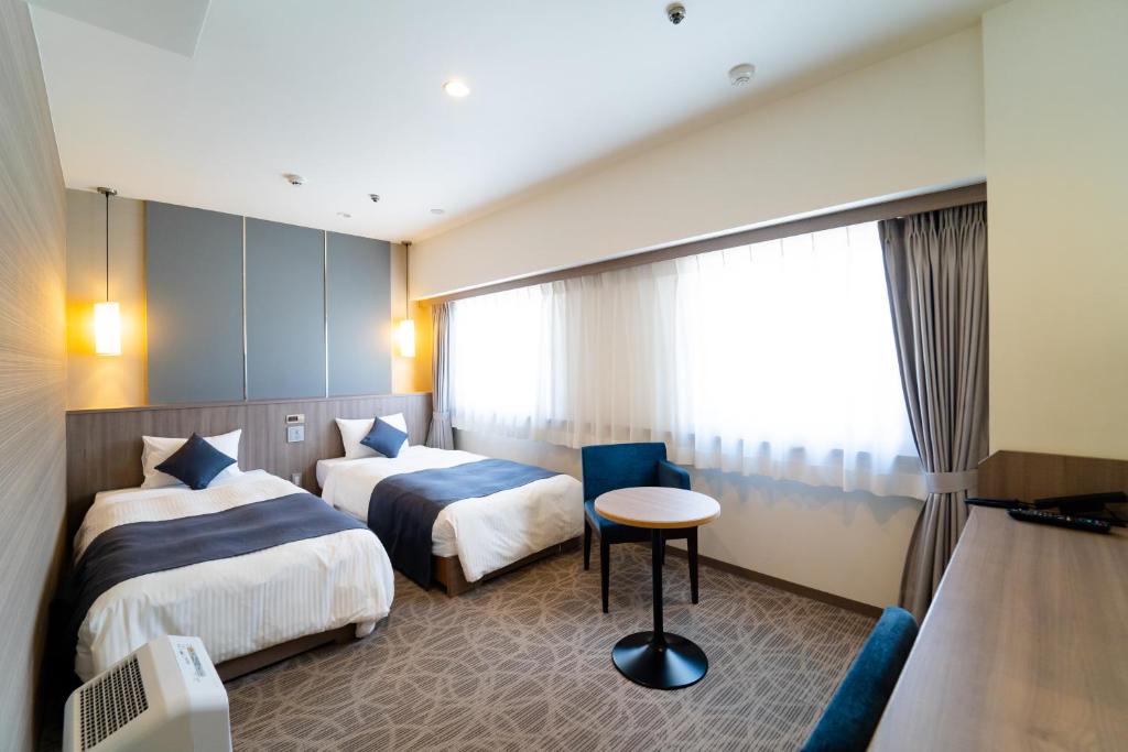 金泽金泽花园酒店的酒店客房设有两张床和一张桌子。