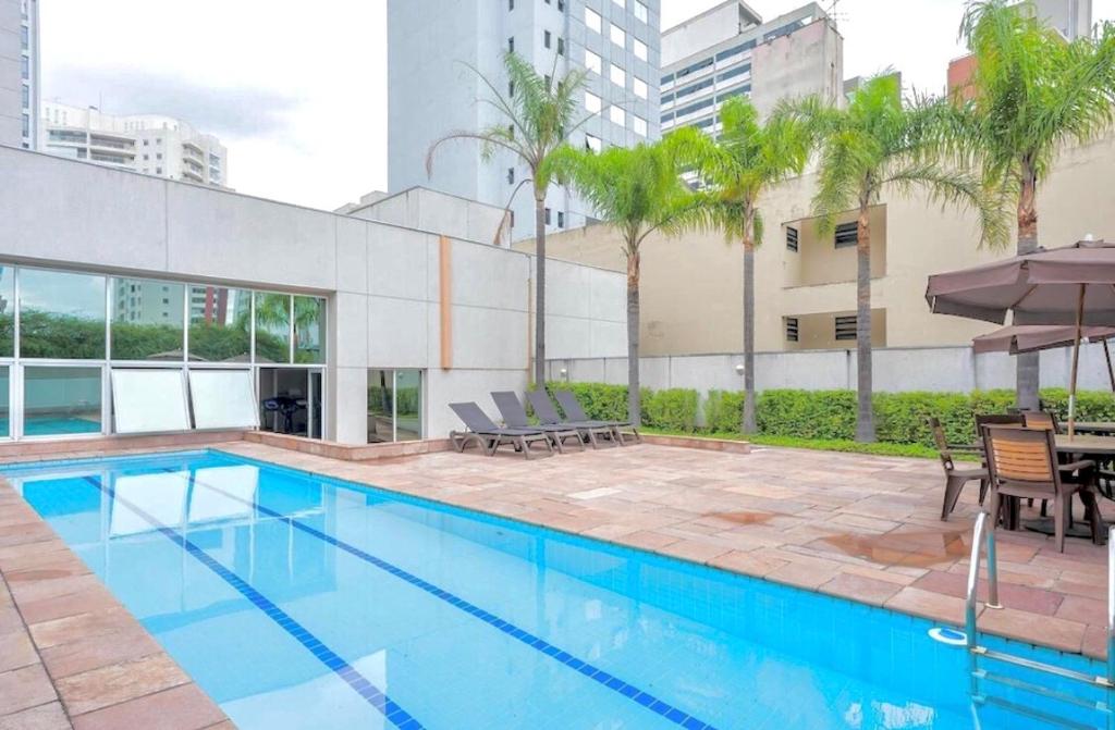 圣保罗Flat em Hotel na Bela Cintra próximo à Paulista e Consolação的大楼旁的游泳池配有桌椅