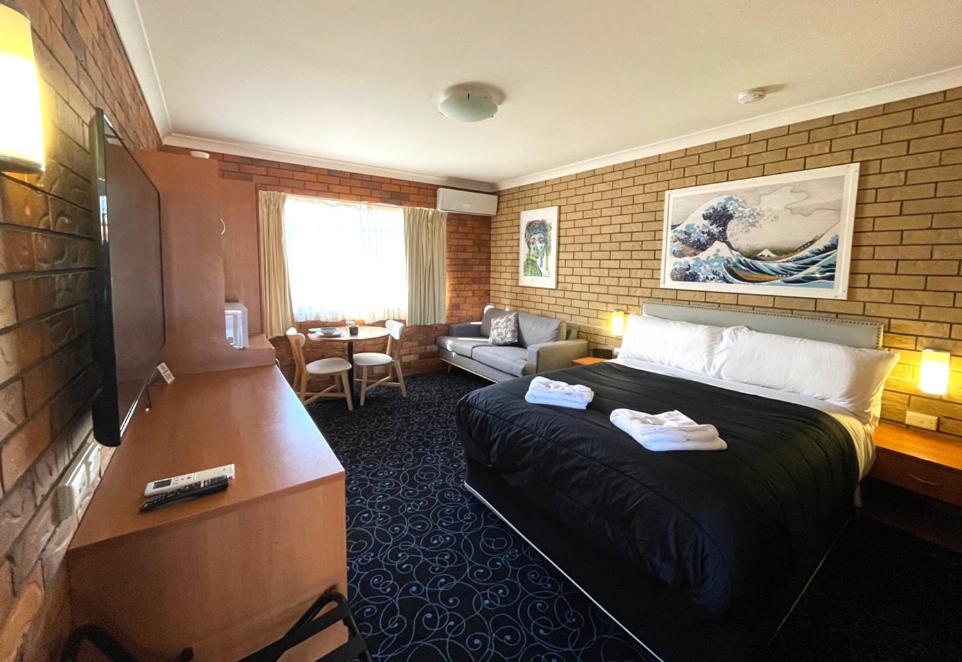 GuyraShiralee Motel Guyra的酒店客房设有床和客厅。
