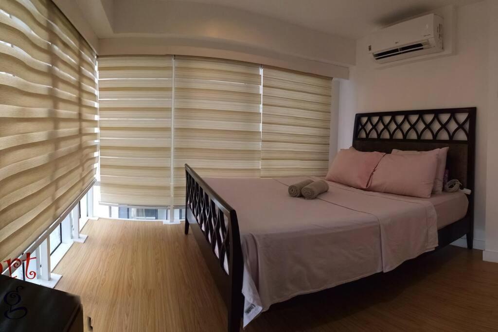 马尼拉2 BR loft-type condo Fort Victoria的一间卧室配有一张床和一个带百叶窗的窗户