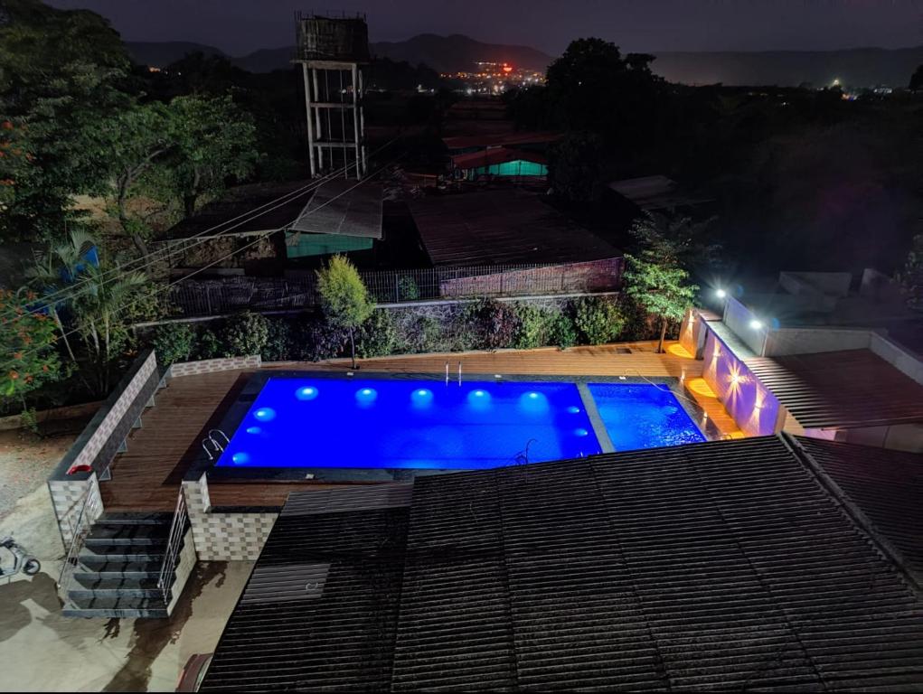 罗纳瓦拉Chandra Villa 12Bhk Lonavala的一座游泳池,在晚上在一座建筑的顶部