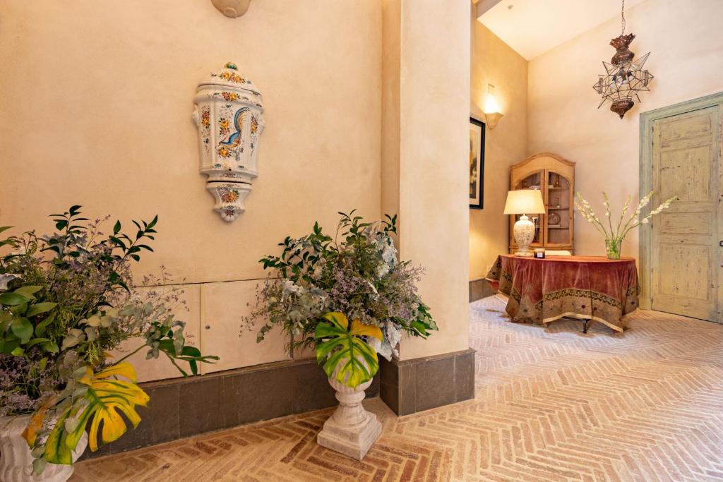 塞维利亚Casa de la Moneda Residences Sevilla的种植了植物的走廊和配有桌子的房间
