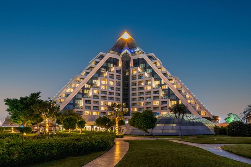 迪拜迪拜莱福士酒店的一座高大的建筑,在晚上有金字塔形的屋顶