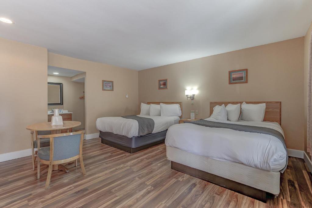 BurneyShasta Pines Motel &amp; Suites的有两张床和一张桌子的酒店房间