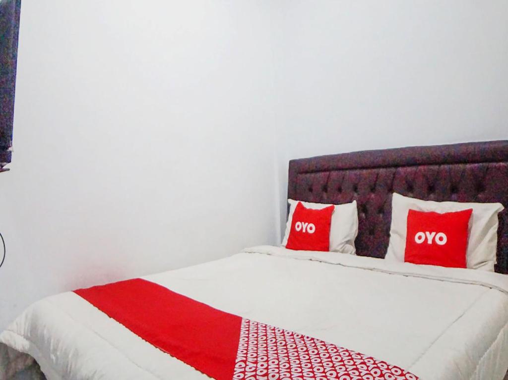 棉兰SUPER OYO 91627 Wika Wiki Homestay的床上有两个红色枕头的床