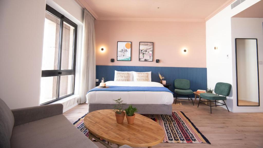 特拉维夫Selina Tel Aviv Beach的一间卧室配有一张床、一张桌子和一张沙发