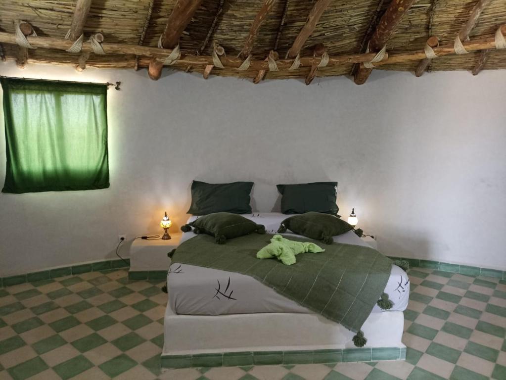 AmizmizLes Jardins d Amizmiz的一间卧室,床上有一只绿色的填充动物