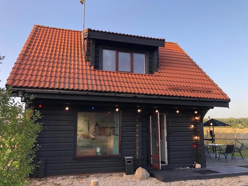 斯伽尔达Vanaga namiņš的一座带橙色屋顶的小房子,设有窗户