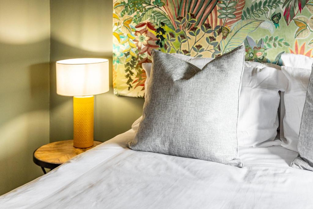 SuttertonMrs Hortons Guest Rooms的一张带枕头的床和一张桌子上的台灯