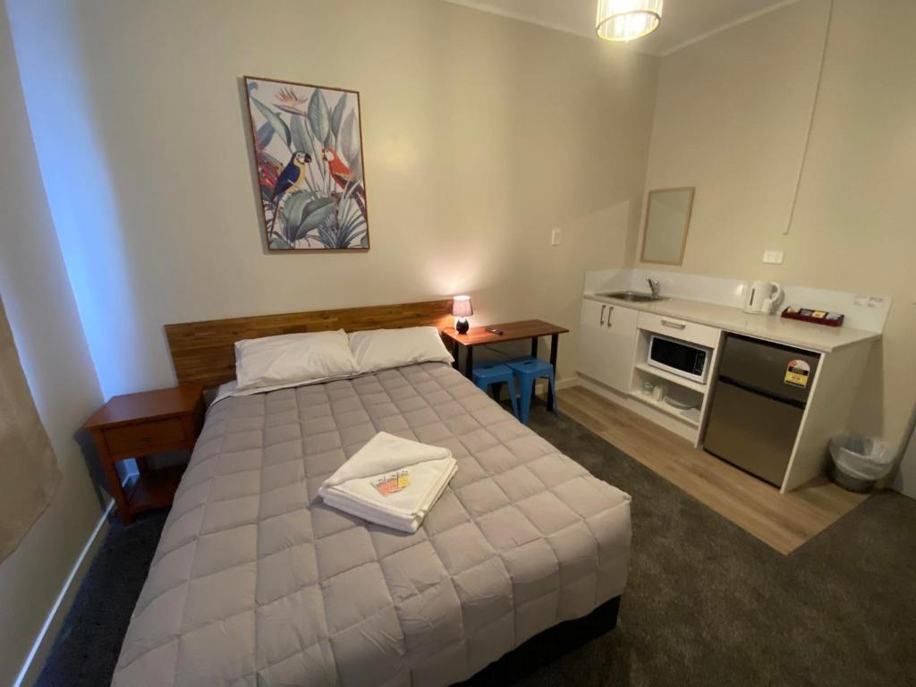 奥克兰Airport Westney Lodge的一间卧室配有一张床和一个小厨房