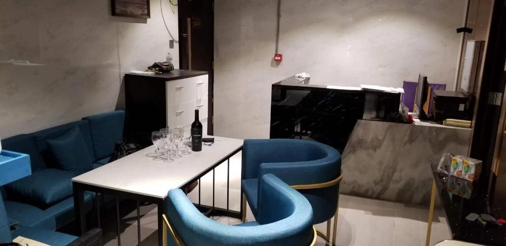 香港Sleep Cubee Hostel的餐厅设有蓝色的椅子和一张桌子及一瓶葡萄酒