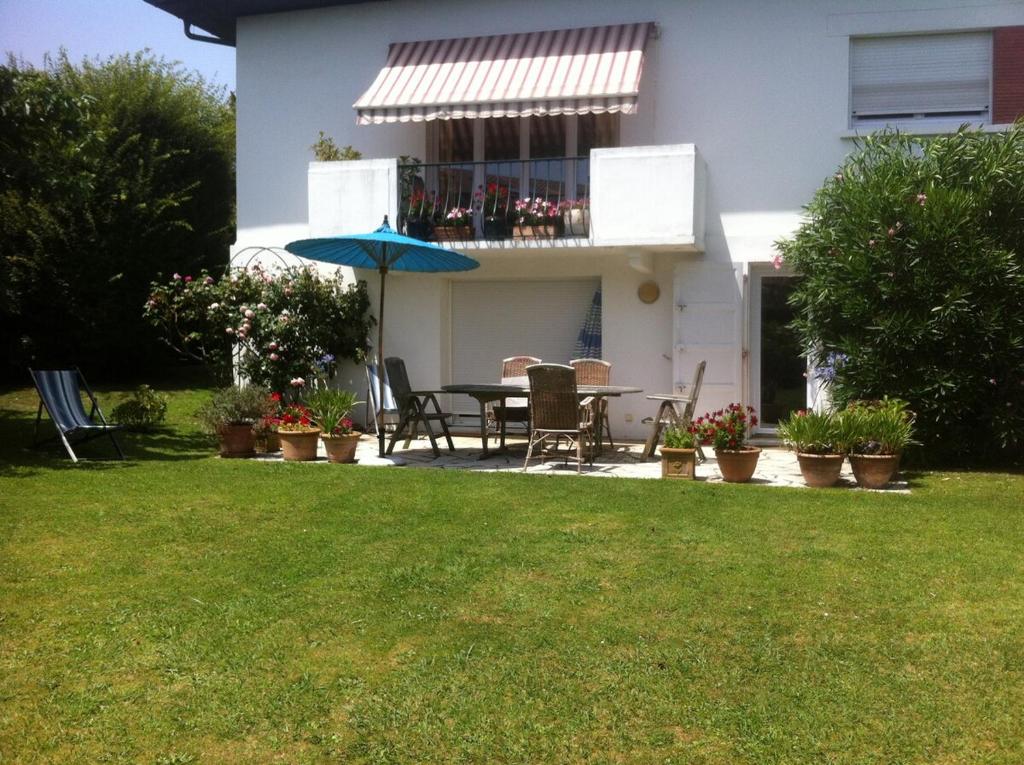 安格雷T1 ou T2 dans villa avec jardin proche Biarritz的庭院里设有带桌子和遮阳伞的庭院。
