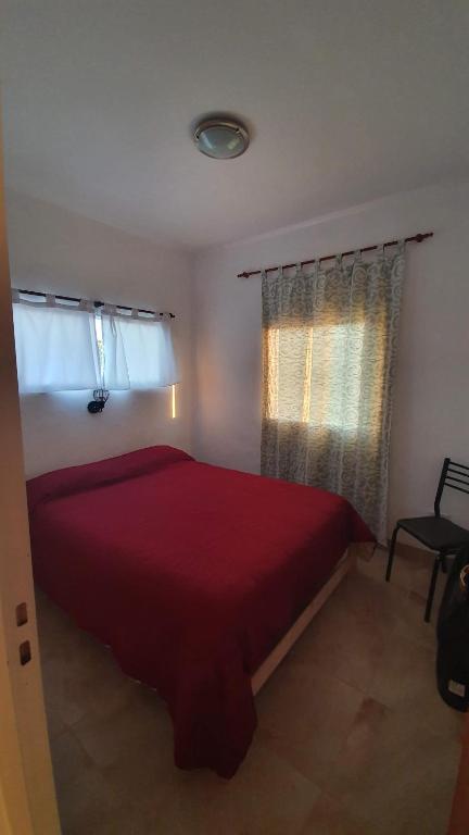 维多利亚Cabañas Atardecer en Victoria的一间卧室设有红色的床和2个窗户。