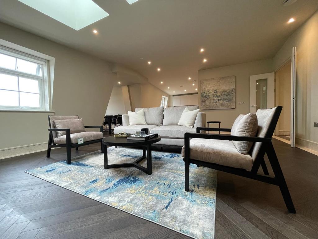 齐格威尔luxurious, 2 bed, 2 bath penthouse apartment in highly desirable Chigwell CHCL F8的客厅配有沙发、椅子和桌子