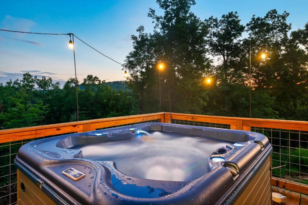赛维尔维尔Ultimate Summer Escape! Cabin-Hot Tub-Cozy-Views-Minutes2Fun的树荫甲板上的按摩浴缸