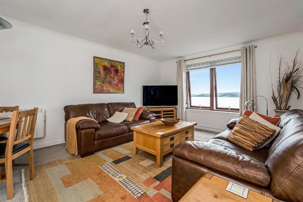 拉格斯Penthouse Seafront Largs的客厅配有真皮沙发和桌子