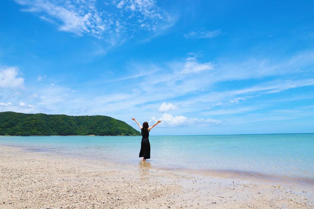 奄美島の宿　結んちゅ的一位手臂伸出双臂站在海滩上的女人