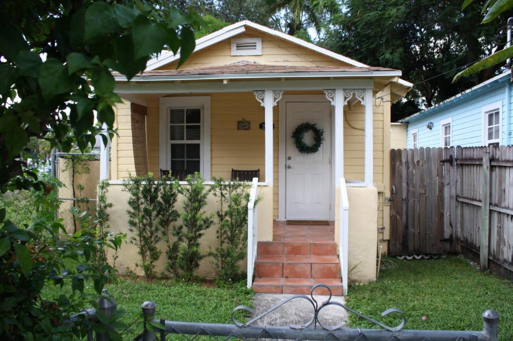 迈阿密Key West Style Historic Home in Coconut Grove Florida The Yellow House的白色门的小黄色房子