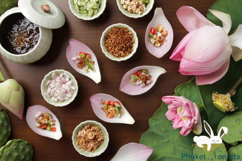 普吉镇Phuket Nonnita Boutique Resort - SHA Plus的一张桌子,上面放着许多不同类型的鲜花食物