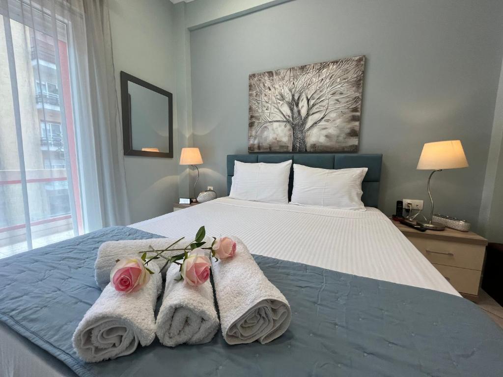 卡瓦拉Kavala Port Apartments的一间卧室配有带毛巾和鲜花的床