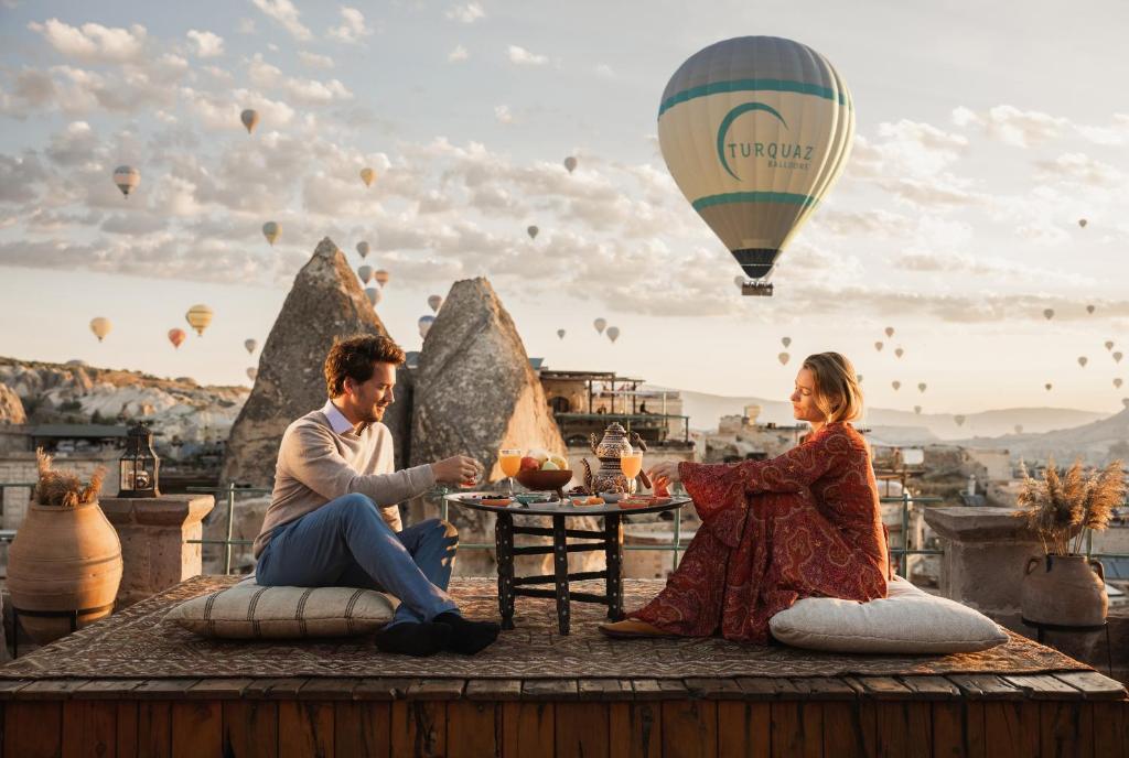 格雷梅苏丹洞穴套房酒店的坐在桌上的男人和女人,带着热气球
