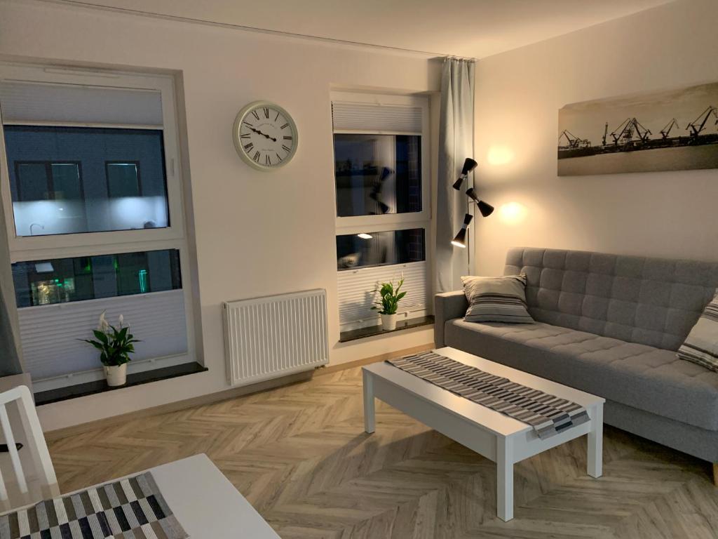 格但斯克Olin Apartament B - Gdańsk Angielska Grobla的客厅配有沙发和墙上的时钟