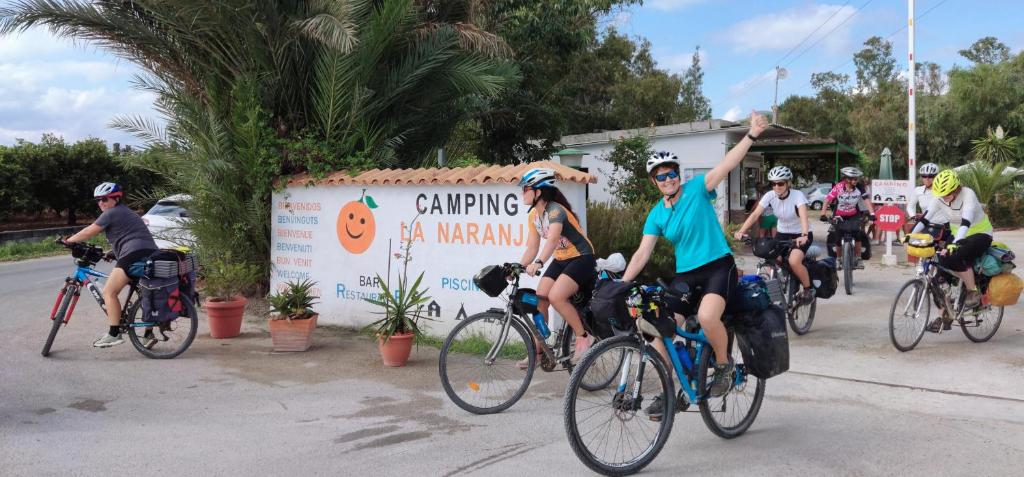 甘迪亚Camping la Naranja的一群人骑着自行车沿着街道走