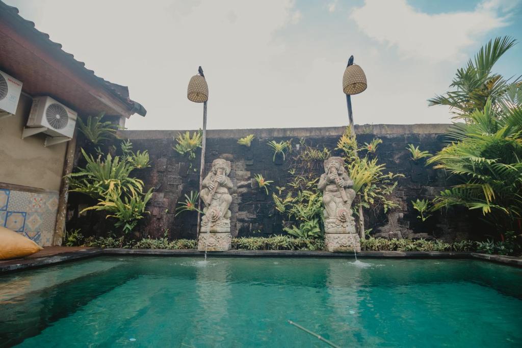 登巴萨萨姆布鲁恩马斯民宿的房屋前的带雕像的游泳池