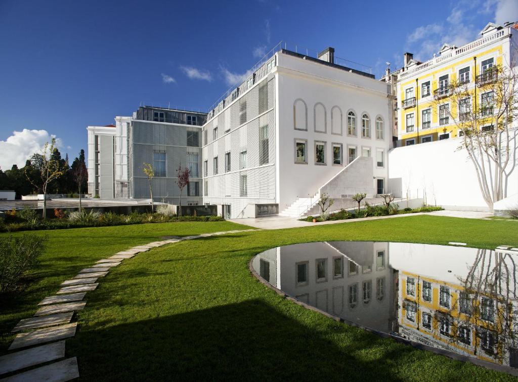 里斯本Hotel da Estrela - by Unlock Hotels的一座白色的大建筑,在草地上反射