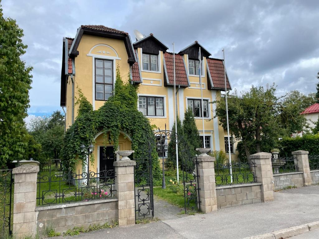 塔尔图Vikerkaare Villa的一座大型黄色房子,设有常春藤围栏