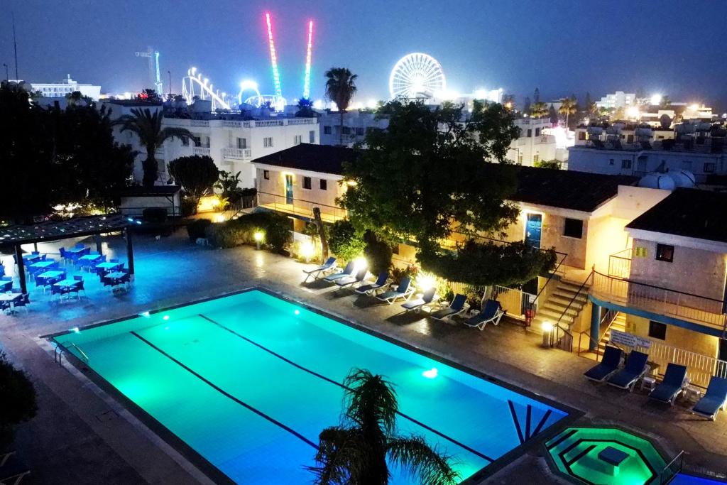 阿依纳帕Green Bungalows Hotel Apartments的夜间游泳池,后面有摩天轮