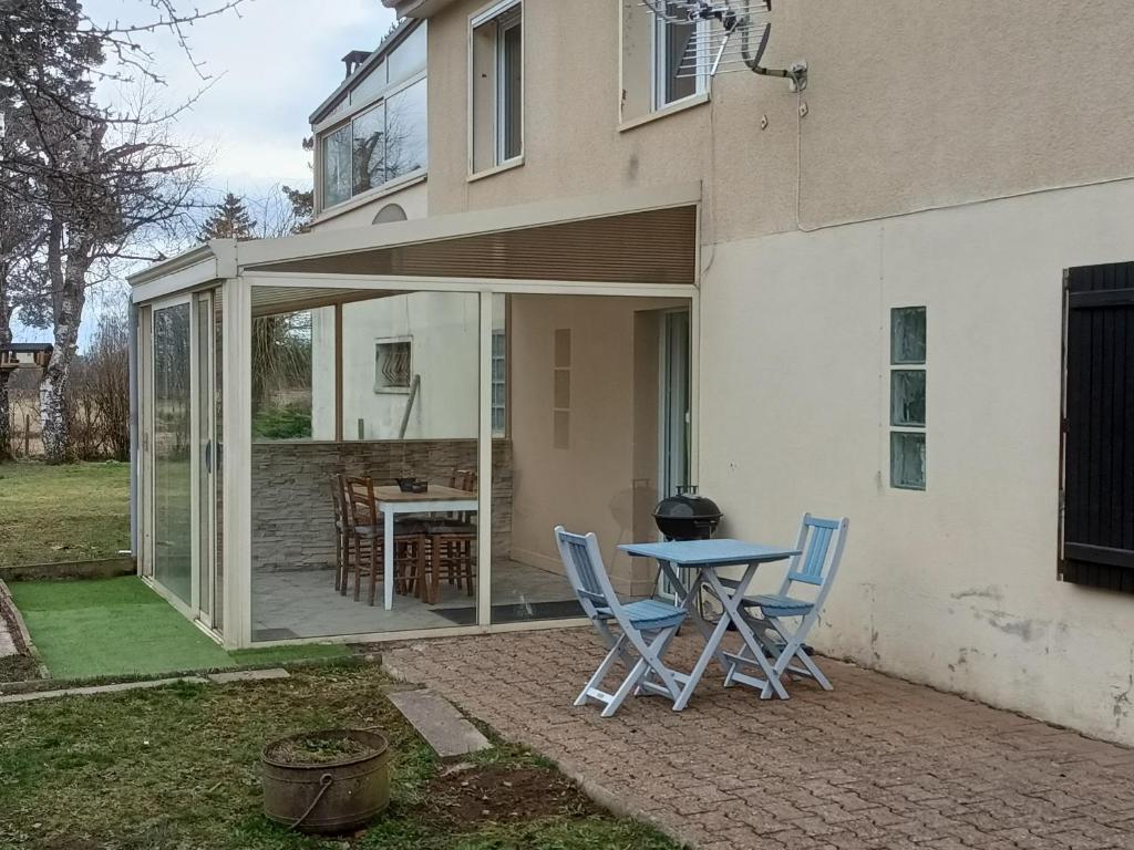 Entre Puy-de-Dôme et Corrèze Appartement pour 4 personnes avec terrasse et jardin的房屋前设有带桌椅的天井。