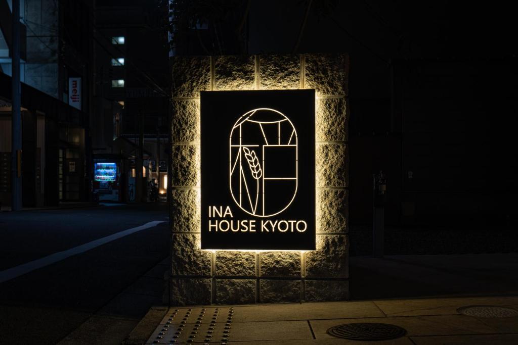 京都INA HOUSE Nijojo的夜间建筑物一侧的标志