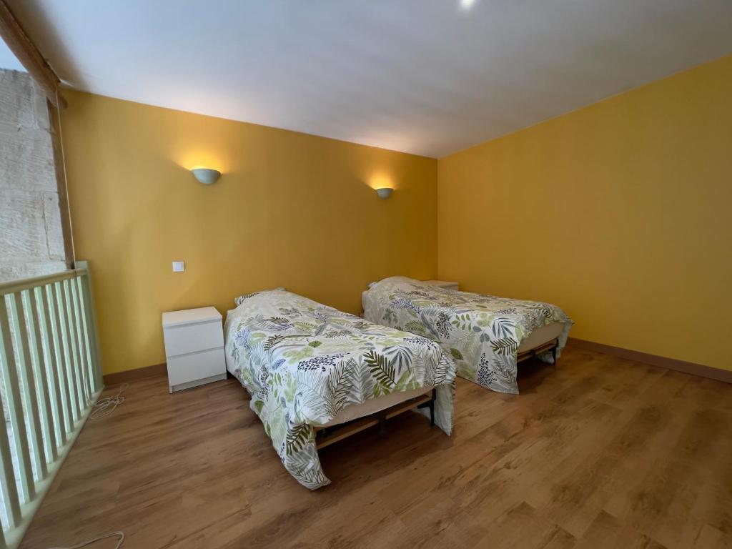 ChâteauvillainLa Maison des Pressoirs的配有黄色墙壁和木地板的客房内的两张床