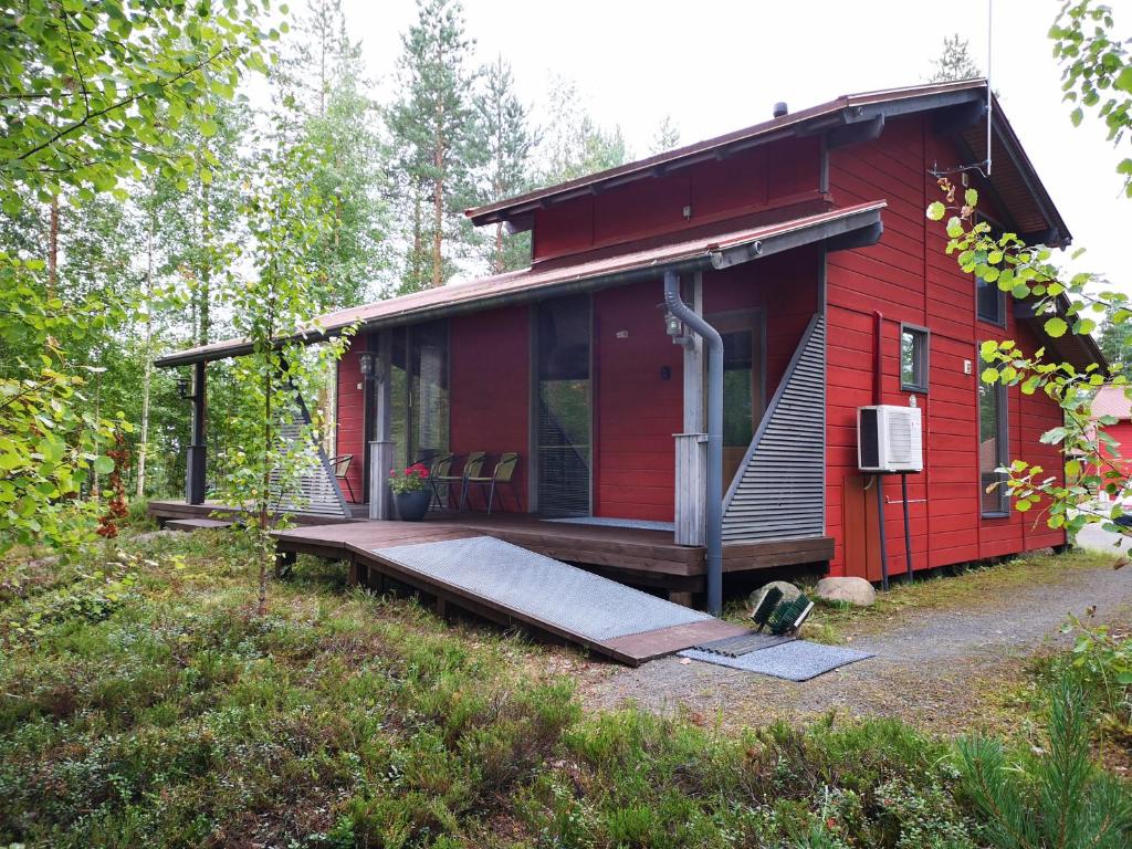 塞伊奈约基Loma-asunto Ahven, Kalajärvi, Maatilamatkailu Ilomäen mökit的红色小屋,在树林里设有门廊