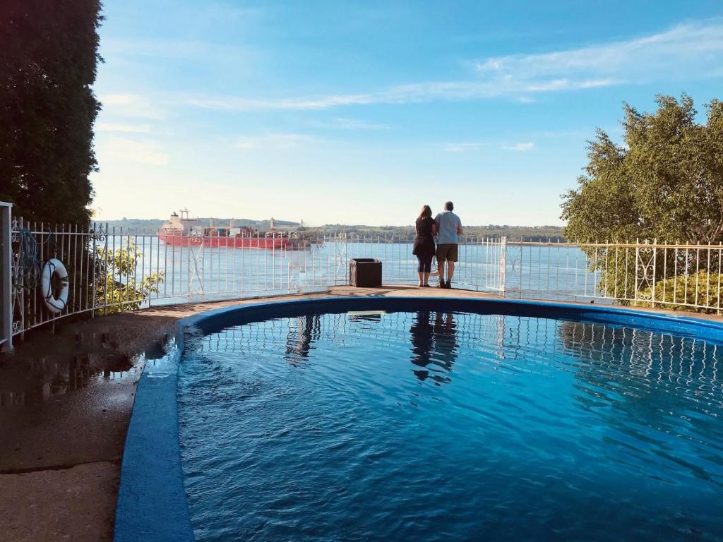 Saint-Laurent-de-l'ile d'OrleansGoéliche hotel et appartement的两人站在游泳池旁,俯瞰水面
