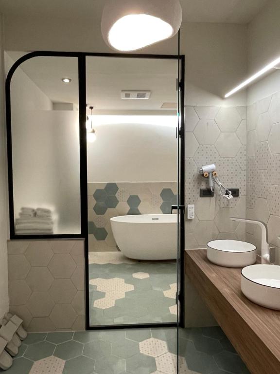 高雄温式旅所 的带浴缸、两个盥洗盆和淋浴的浴室。