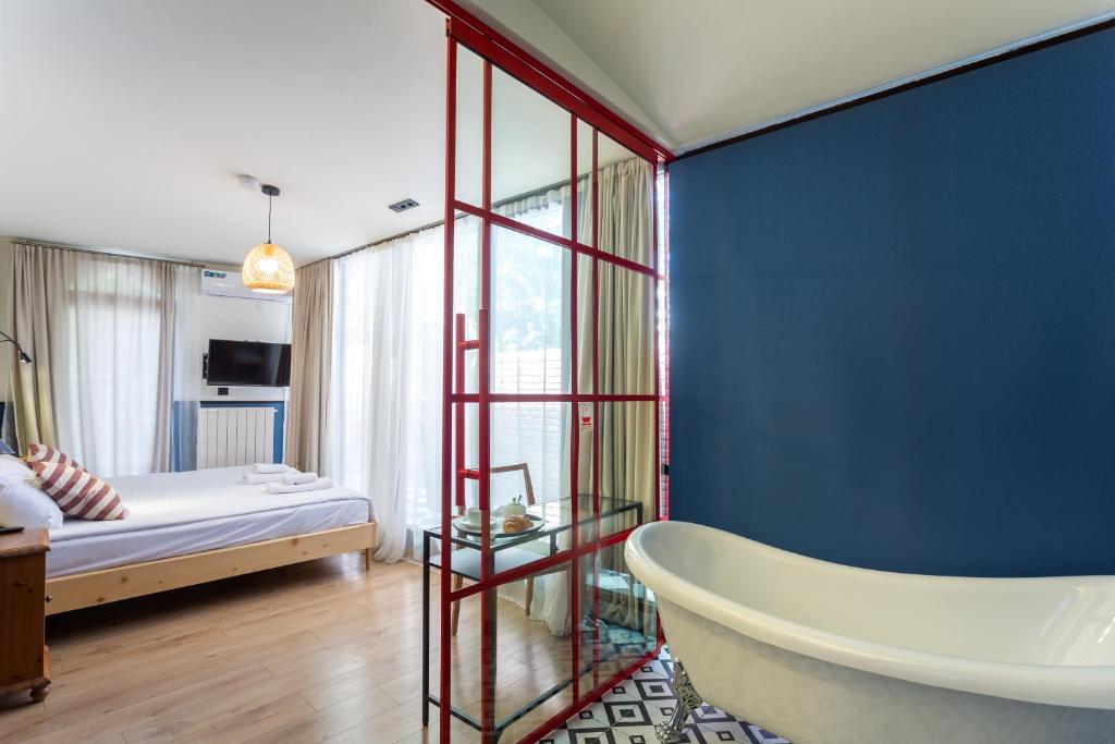 第比利斯Shota Rustaveli Aparthotel的带浴缸、床和蓝色墙壁的浴室