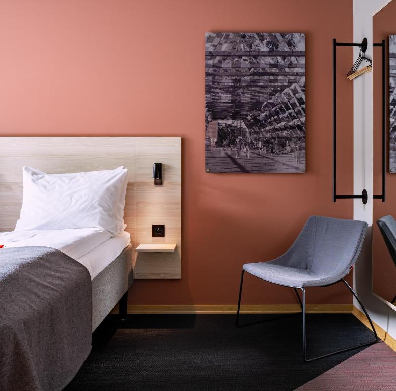 奥斯陆奥斯陆城市之盒酒店的一间卧室配有一张床和一把椅子