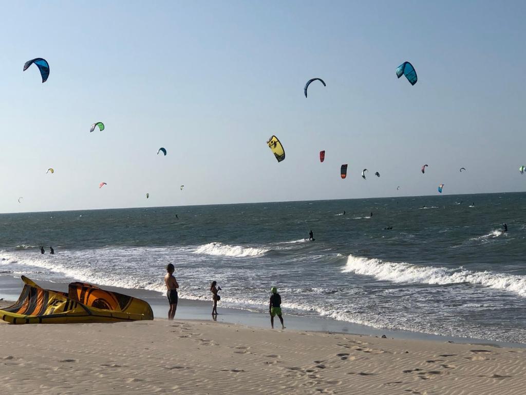 考卡亚Diversão, férias, casa na praia de cumbuco.的一群在海滩上飞风筝的人