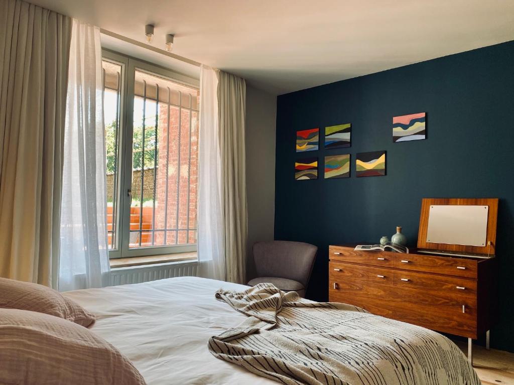 那慕尔Maison Henri Namur的一间卧室配有一张床、一个梳妆台和一扇窗户。