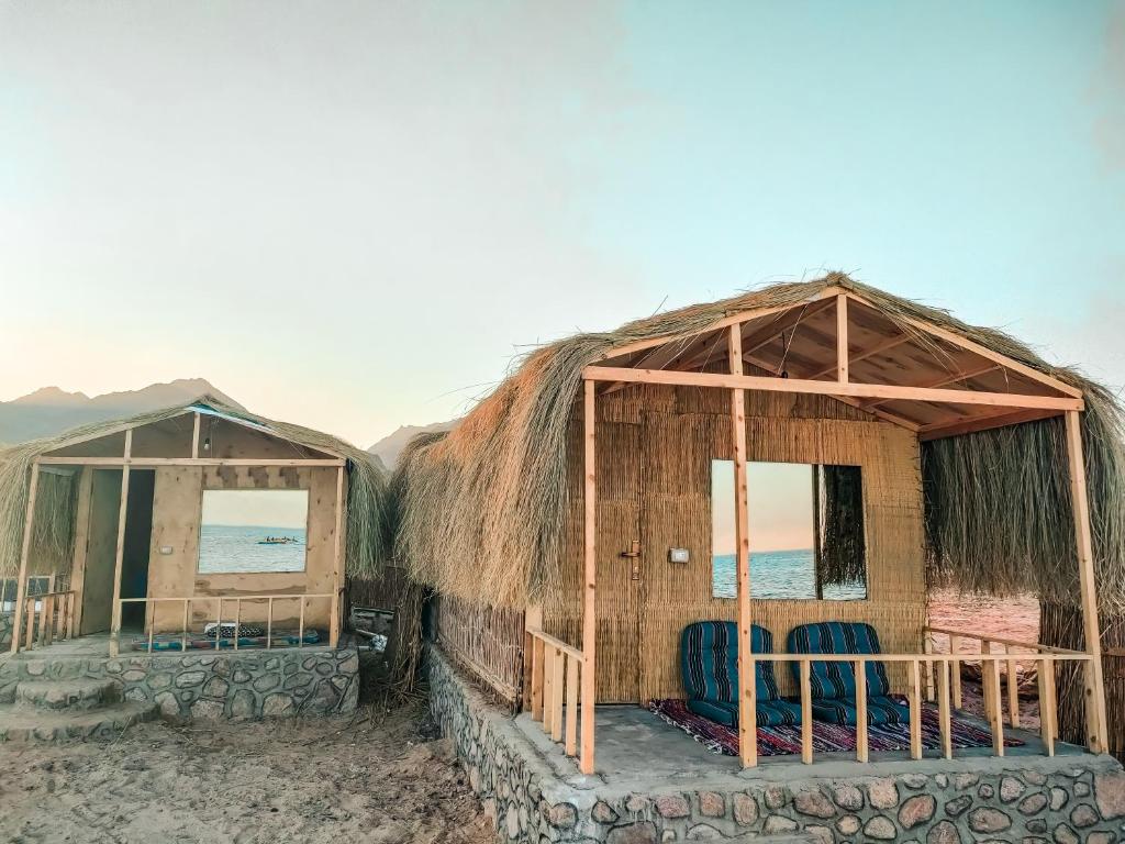 努韦巴Sinai Life Beach Camp的海滩上的两座小屋,配有椅子
