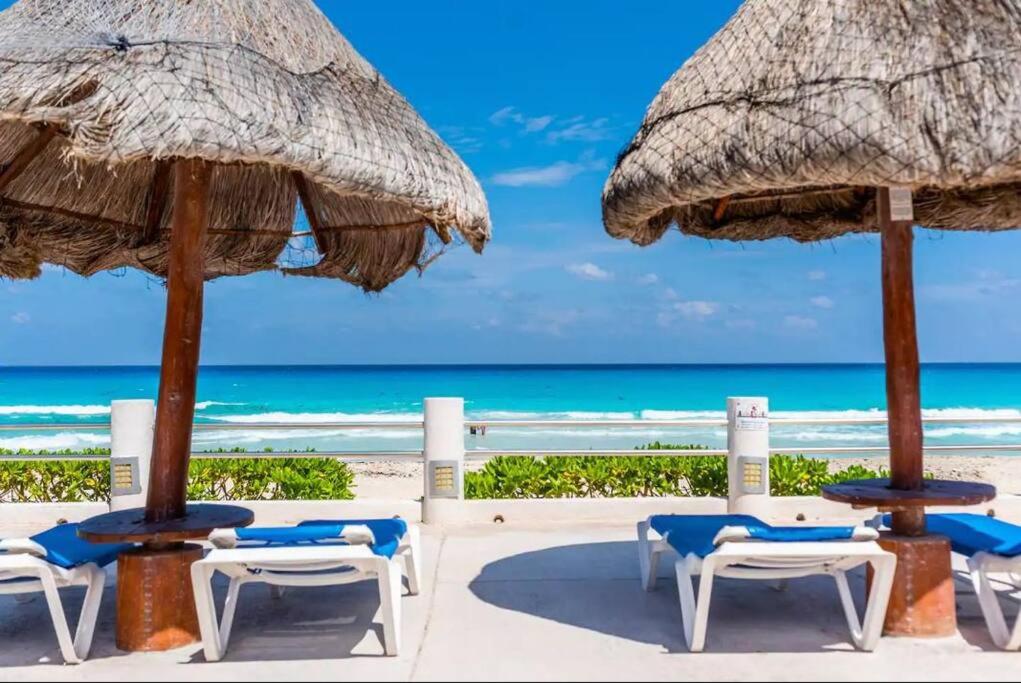 坎昆Villas Marlin by Andiani Travel的海滩上的一组椅子和遮阳伞