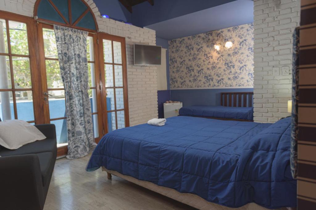 圣胡安讷沃苏左酒店的一间卧室配有蓝色的床、一张沙发和窗户。