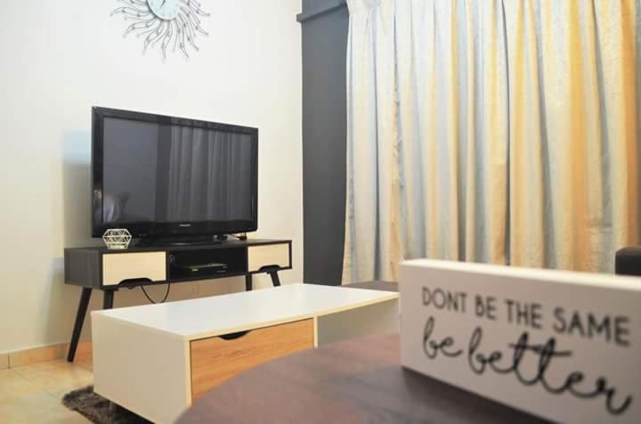 Kampong Batu LapanMH Homestay B Tambun的客厅配有电视和带标志的桌子