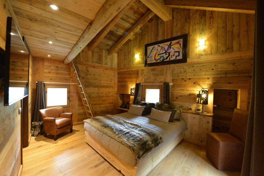 布吕松迷人的多尔夫小木屋及艺术画廊住宿加早餐旅馆的小木屋内的卧室,配有一张床和椅子