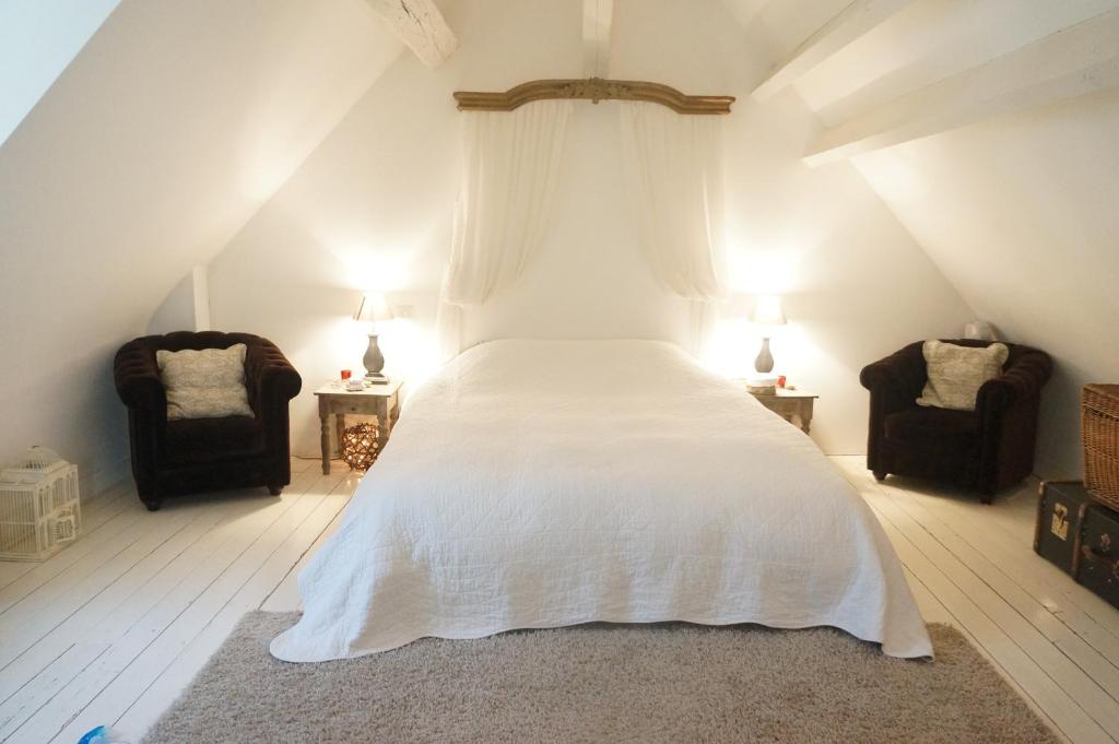 图尔独立度假屋的一间卧室配有一张带白色床单的床和两把椅子