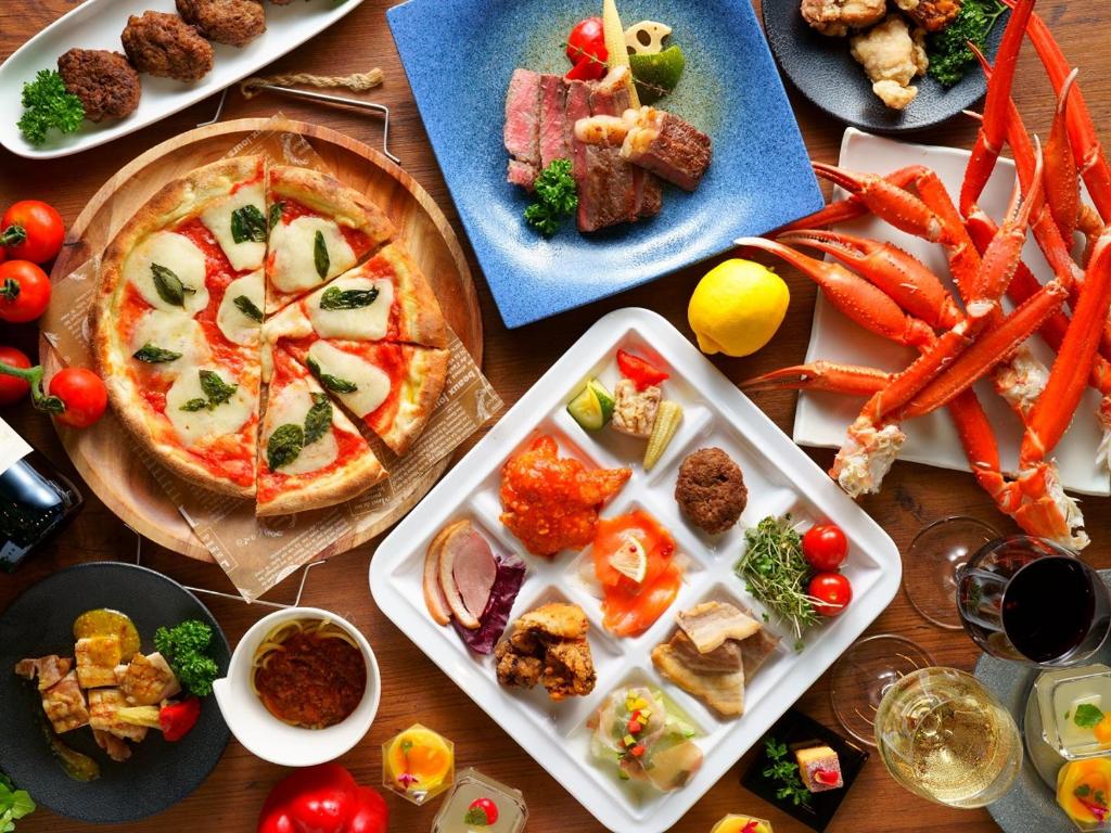 阿苏市格兰德里奥麻生度假酒店的餐桌上摆放着食物盘子和比萨饼